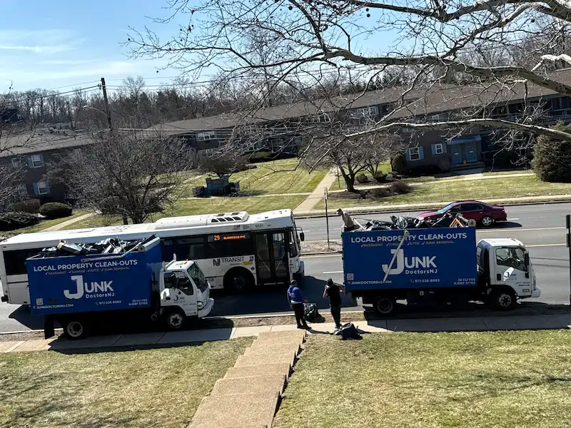Two JunkDoctors 25-yard trucks performing a large-scale apartment cleanout next to an NJ Transit bus in New Jersey.