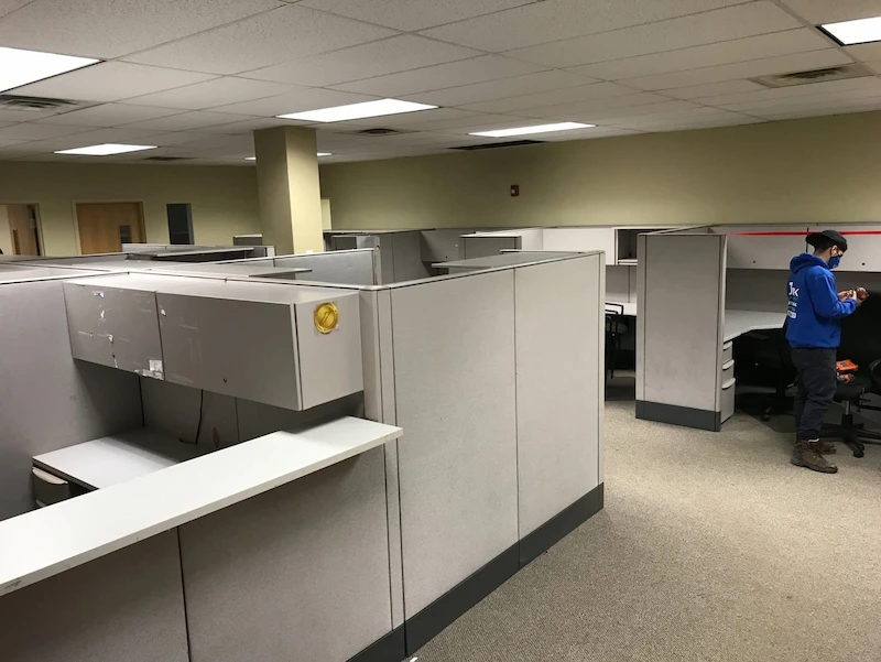 Before photo: JunkDoctors NJ crew member dismantling heavy cubicles and desks during a commercial office cleanout in New Jersey.