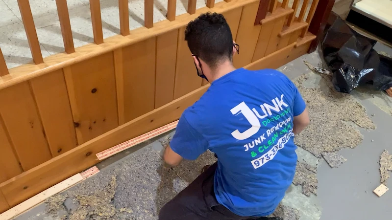 Junk Doctors NJ crew member performing a professional carpet rip-out and padding removal in a commercial building.