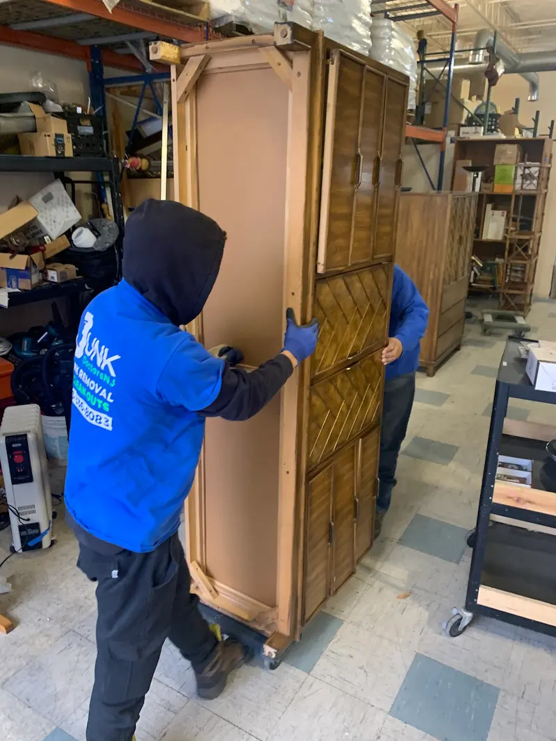 JunkDoctors crew using professional moving equipment to haul away heavy office furniture in a North Jersey commercial facility.
