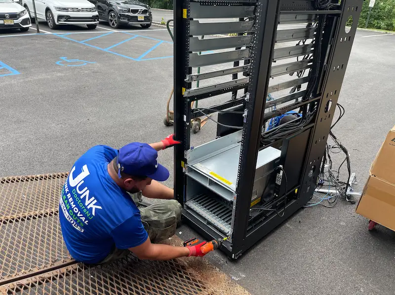 JunkDoctors crew using power tools to dismantle a heavy IT server rack during a commercial office cleanout in New Jersey.