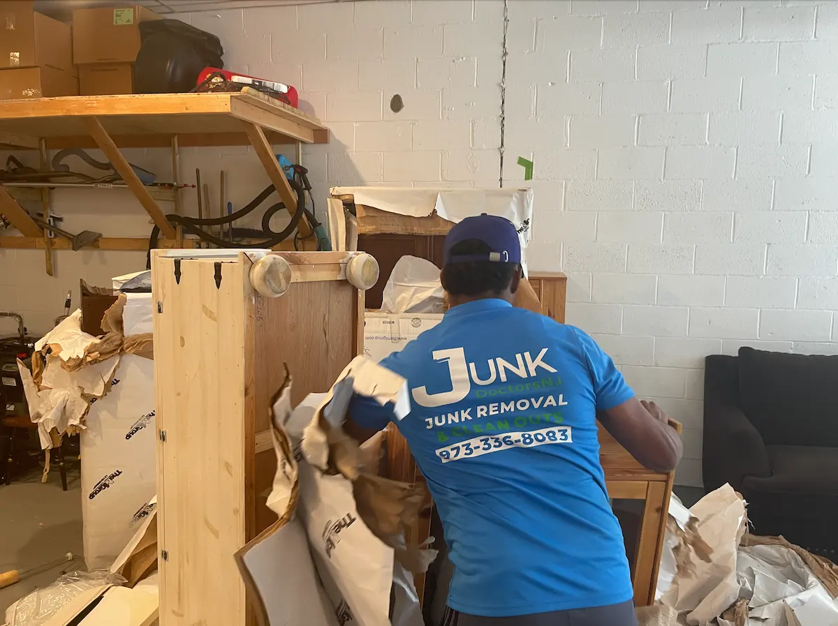 Professional JunkDoctors team member hauling away old wooden furniture and packaging debris during a commercial backroom cleanout.