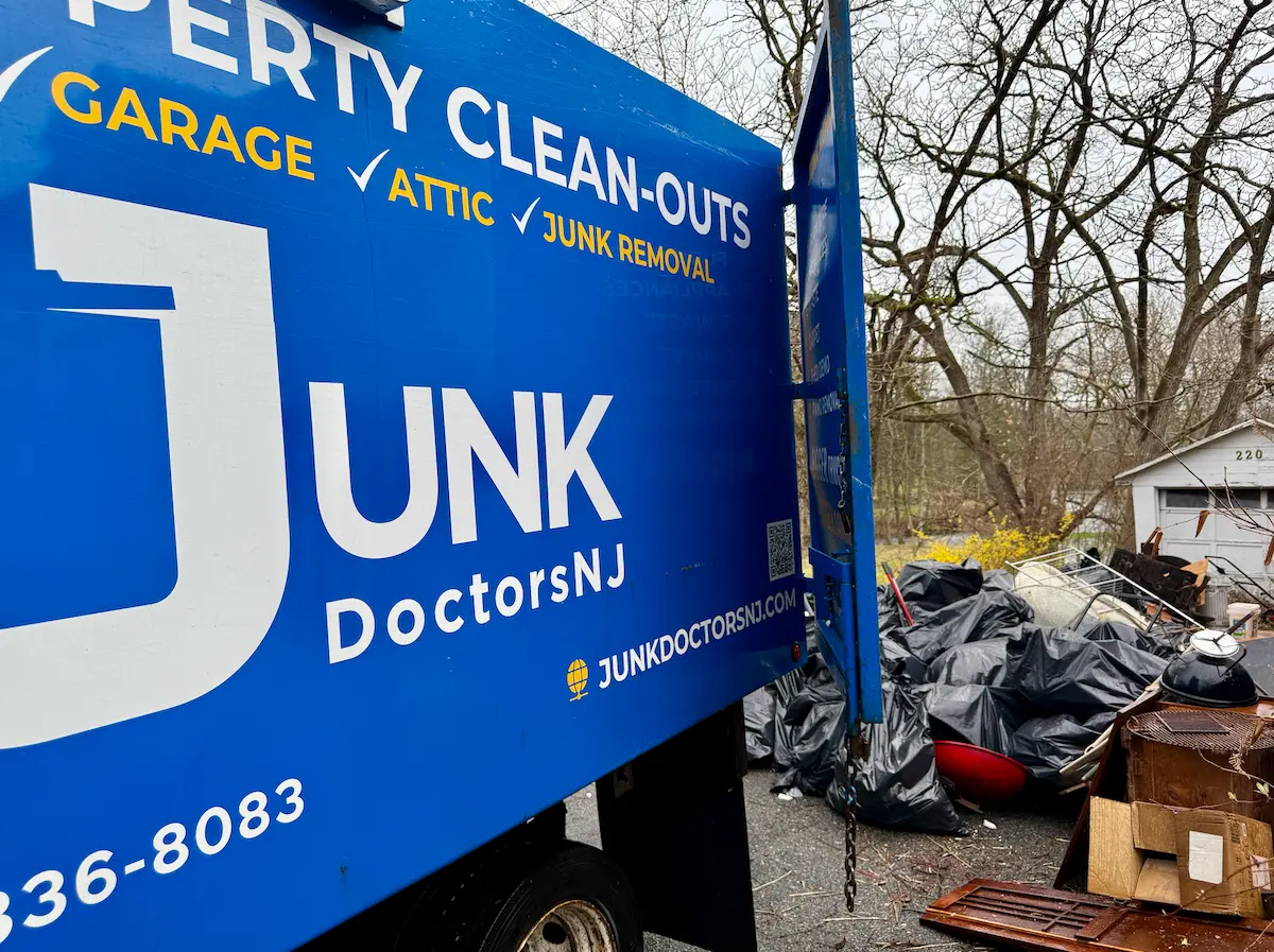 A large pile of bagged debris and old household junk hauled out of a dirty residential crawl space, ready to be loaded into a New Jersey JunkDoctors truck.