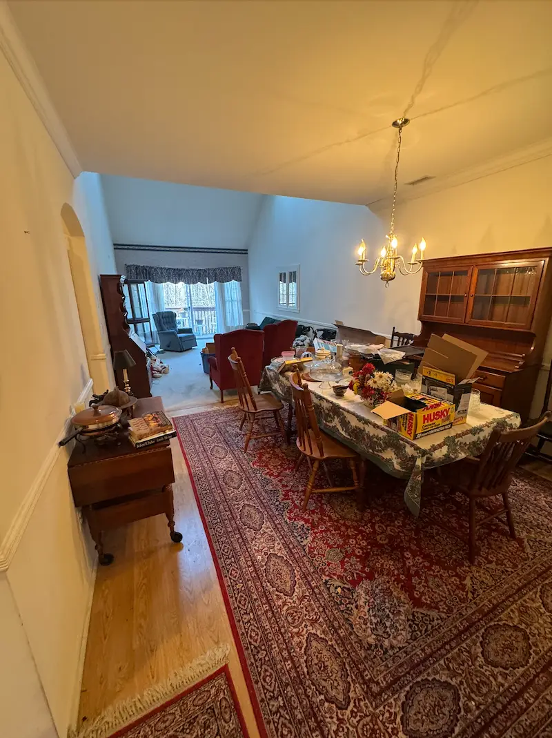 Before photo of a large NJ dining room filled with heavy wood furniture, chairs, and household items before a JunkDoctors house cleanout.