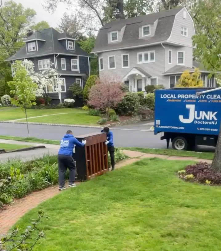 Junk Doctors NJ crew members carefully moving a heavy upright piano down a residential walkway for removal and disposal in North NJ.