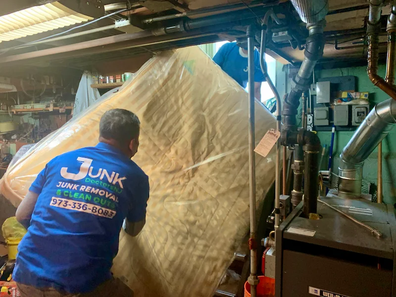 Junk Doctors professional junk removal team picking up a queen size mattress from a residential basement.