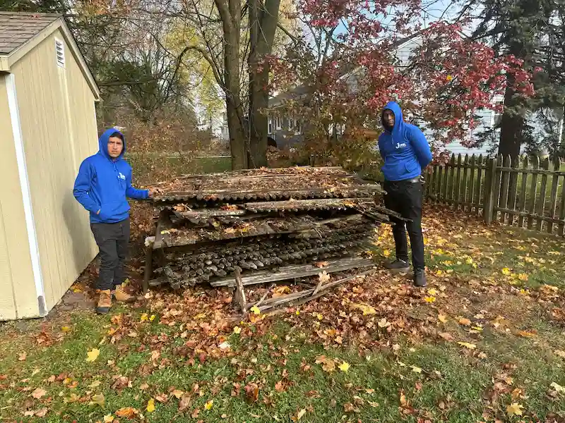 JunkDoctors crew clearing out old wood and exterior debris from a backyard shed area in New Jersey.