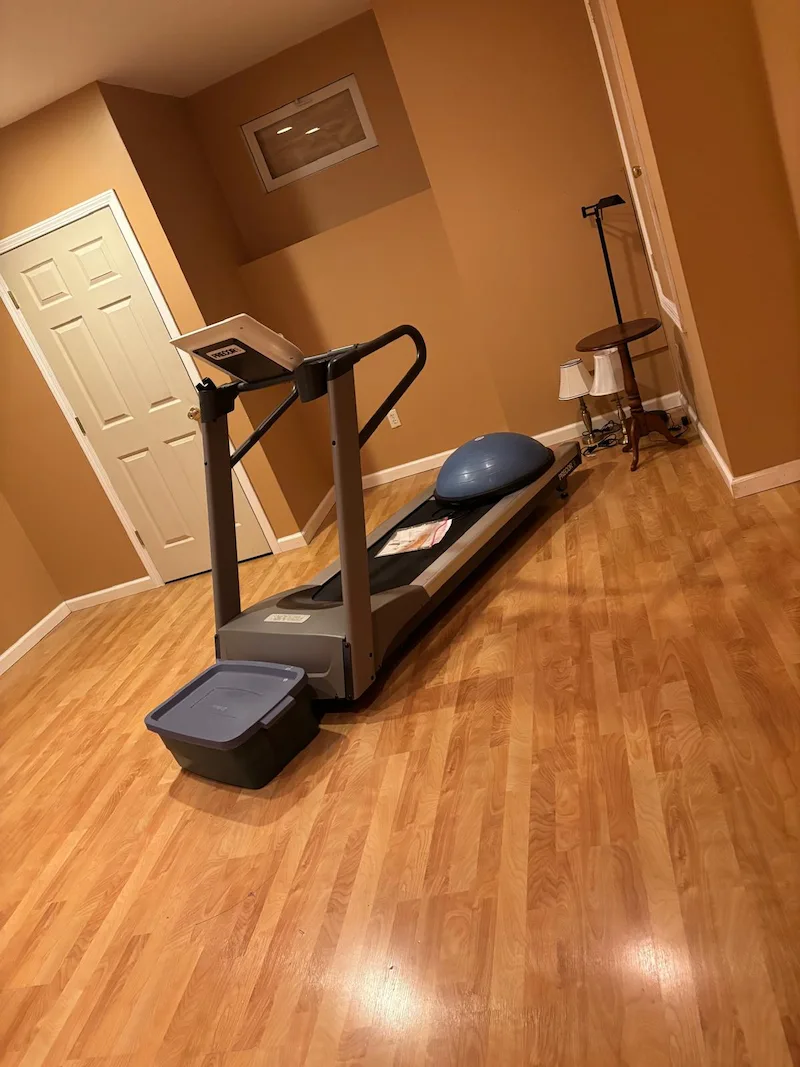 Heavy Precor treadmill sitting in a finished basement before being removed by JunkDoctors in Ridgewood, New Jersey.
